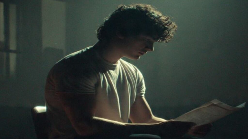 Young boy sitting in a dimly lit room reading an audition script carefully, trying to understand acting failure reason and improve his acting performance