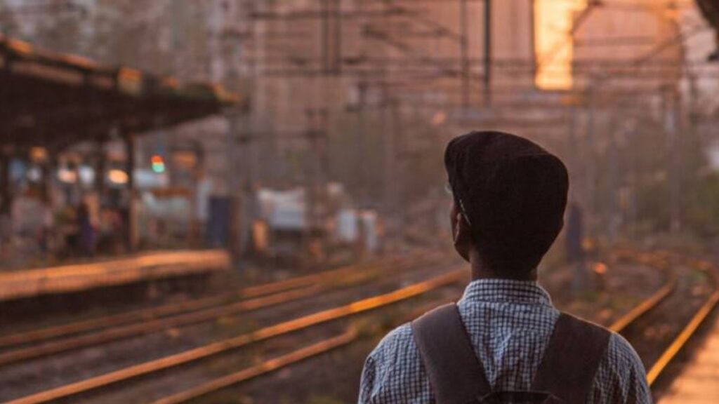 Young boy standing at Mumbai railway station looking at the sky for the first time, thinking about his dreams and acting failure reason in his journey